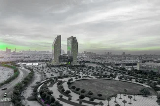 Panoramic view of the Dubai Science Park (DSP) with its two distinctive twin-tower buildings and surrounding landscaped area. The image has a heavy green color splash effect on the sky and buildings.