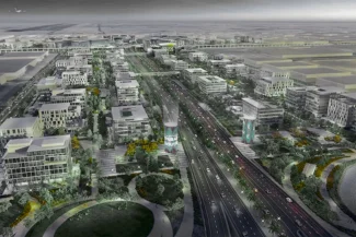 Wide, aerial view of the massive development project Dubai South (formerly Dubai World Central), showing wide central highways and blocks of modern low-rise commercial buildings.