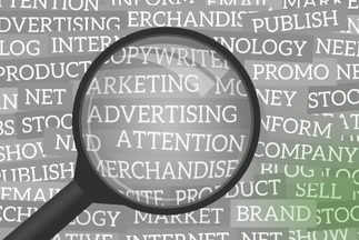 A magnifying glass focusing on key business and marketing terms like 'ADVERTISING', 'MARKETING', and 'BRAND' in a word cloud.