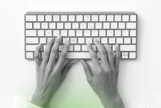 Overhead view of hands typing on a minimalist white keyboard, representing content creation or professional work.