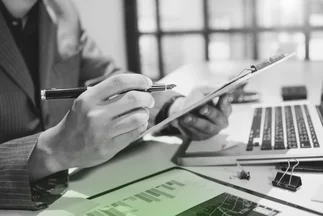 Close-up of a person reviewing a document on a clipboard next to a laptop, indicating content performance analysis or reporting.