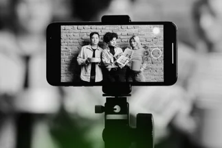 Smartphone on a tripod recording three young people, symbolizing social media video creation, vlogging, or live content.