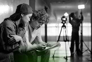 Two young professionals reviewing a script or plans on a set, suggesting video content production or content briefing.